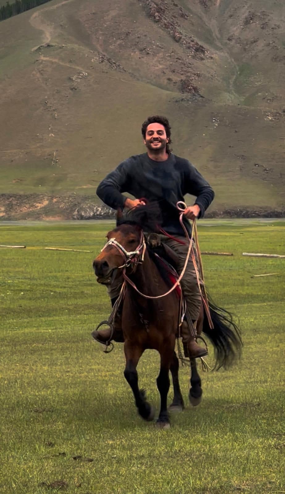 Robert Zaher riding a horse across the Mongolian valley